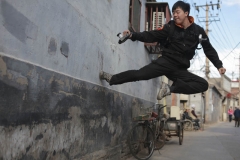 Jeune chinois qui saute sur un mur de Hutong